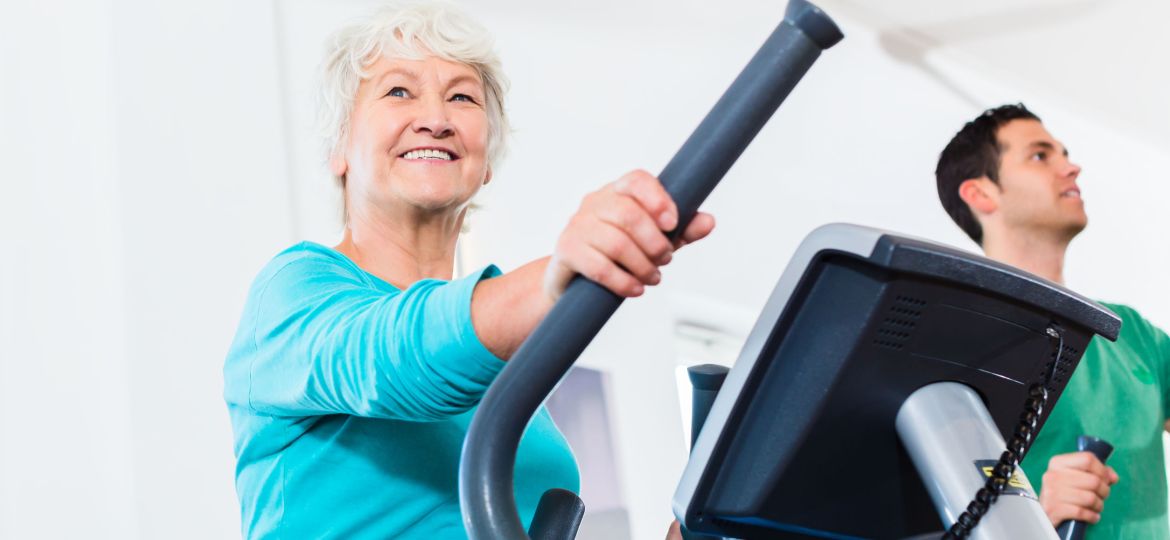 Senior woman on elliptical trainer exercising in gym