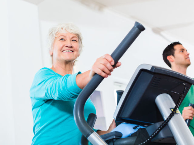 Senior woman on elliptical trainer exercising in gym